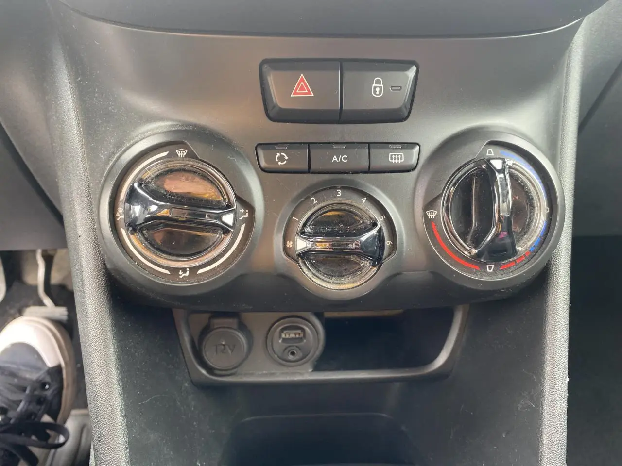 Gros plan sur le bouton de réglage de la température du système de climatisation dans une Peugeot 208 gris 2018.