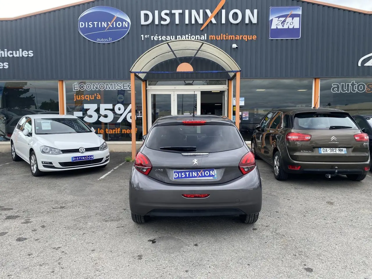 Vue arrière d'une Peugeot 208 gris métallisé garée devant un concessionnaire multimarque Distinxion.
