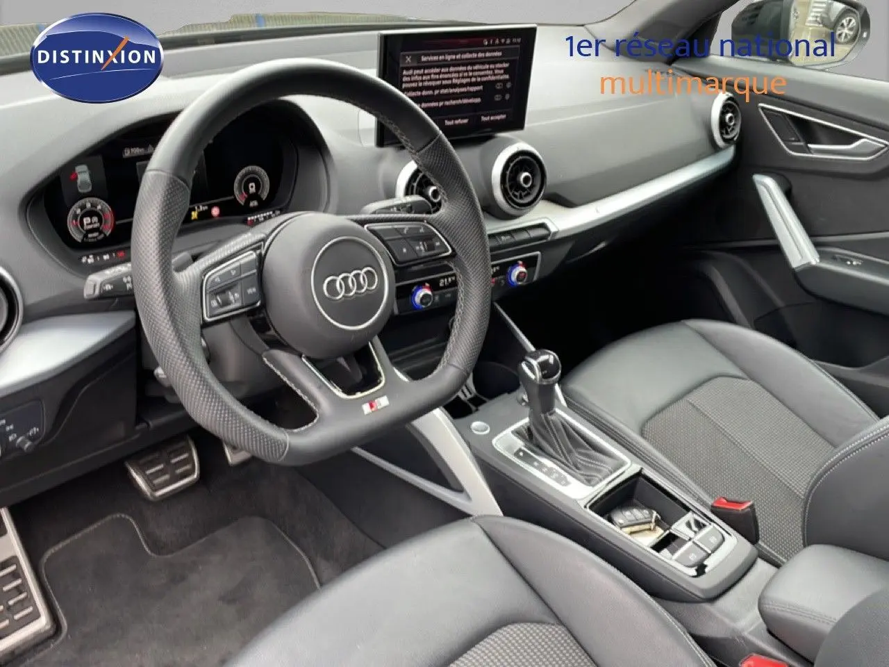 Vue intérieure côté conducteur de l'Audi Q2 35 2.0 TDI S-Line 2025 avec volant cuir perforé et console centrale moderne.