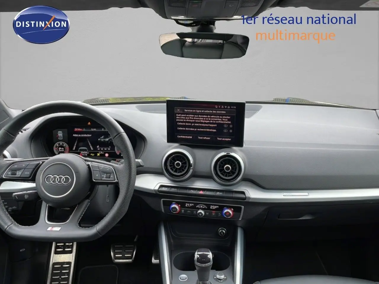 Vue intérieure avant de l'Audi Q2 noir mito metal 2025, volant sport, écran central et commandes climatisation visibles.