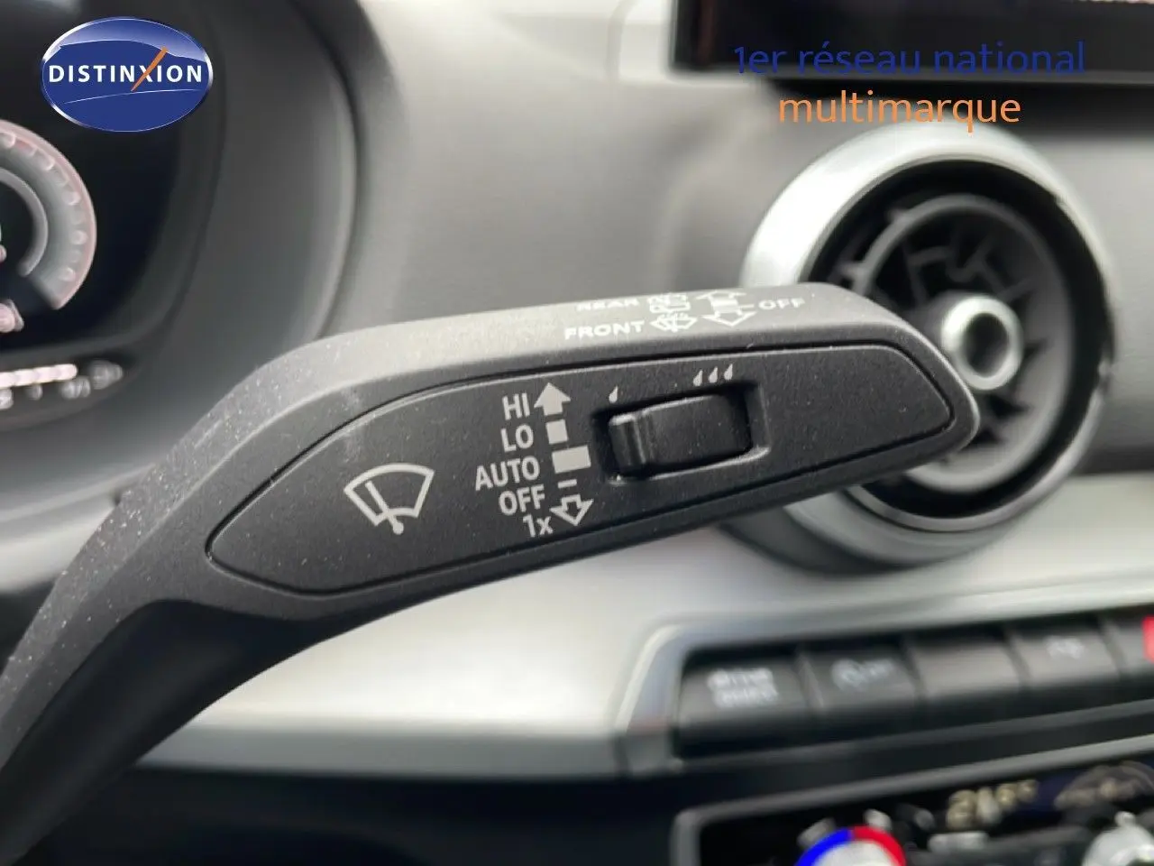 Gros plan sur la commande des essuie-glaces de l'Audi Q2 2025, intérieur noir avec aérateur circulaire en arrière-plan.