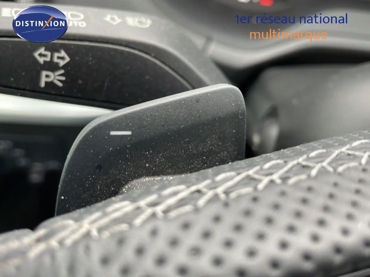 Gros plan sur la palette de changement de vitesse noire et le volant cuir perforé de l’Audi Q2 35 2.0 TDI S-Line.