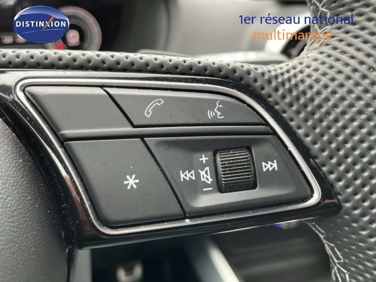 Gros plan sur les commandes noires au volant perforé de l’Audi Q2 noir mito metal, version 35 2.0 TDI S-Line.