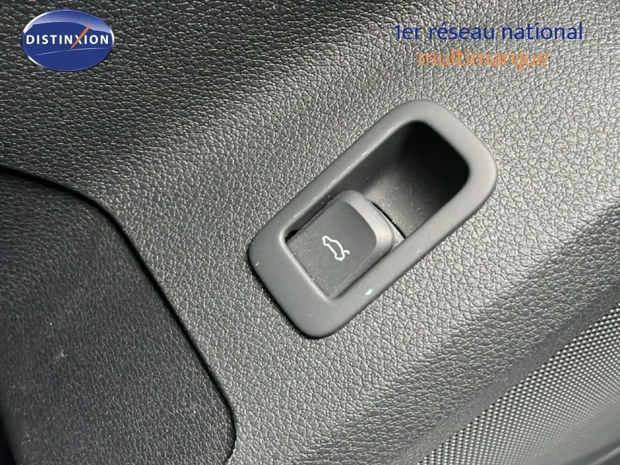 Bouton d'ouverture de coffre intégré dans le revêtement noir texturé de l'Audi Q2 35 2.0 TDI S-Line.