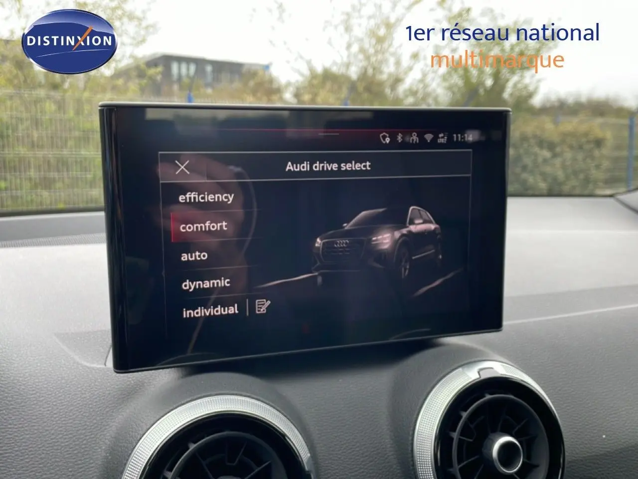 Écran central affichant les modes de conduite avec une image 3/4 avant d’un Audi Q2 noir Mito Metal.