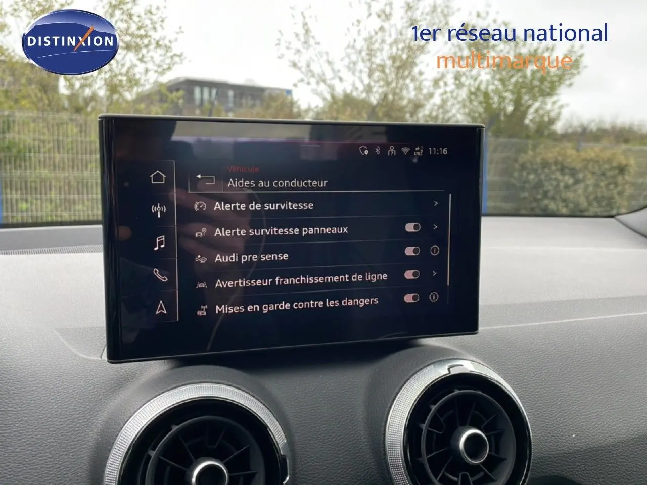Vue intérieure du tableau de bord de l'Audi Q2 noir mito metal, avec écran tactile affichant les aides à la conduite.