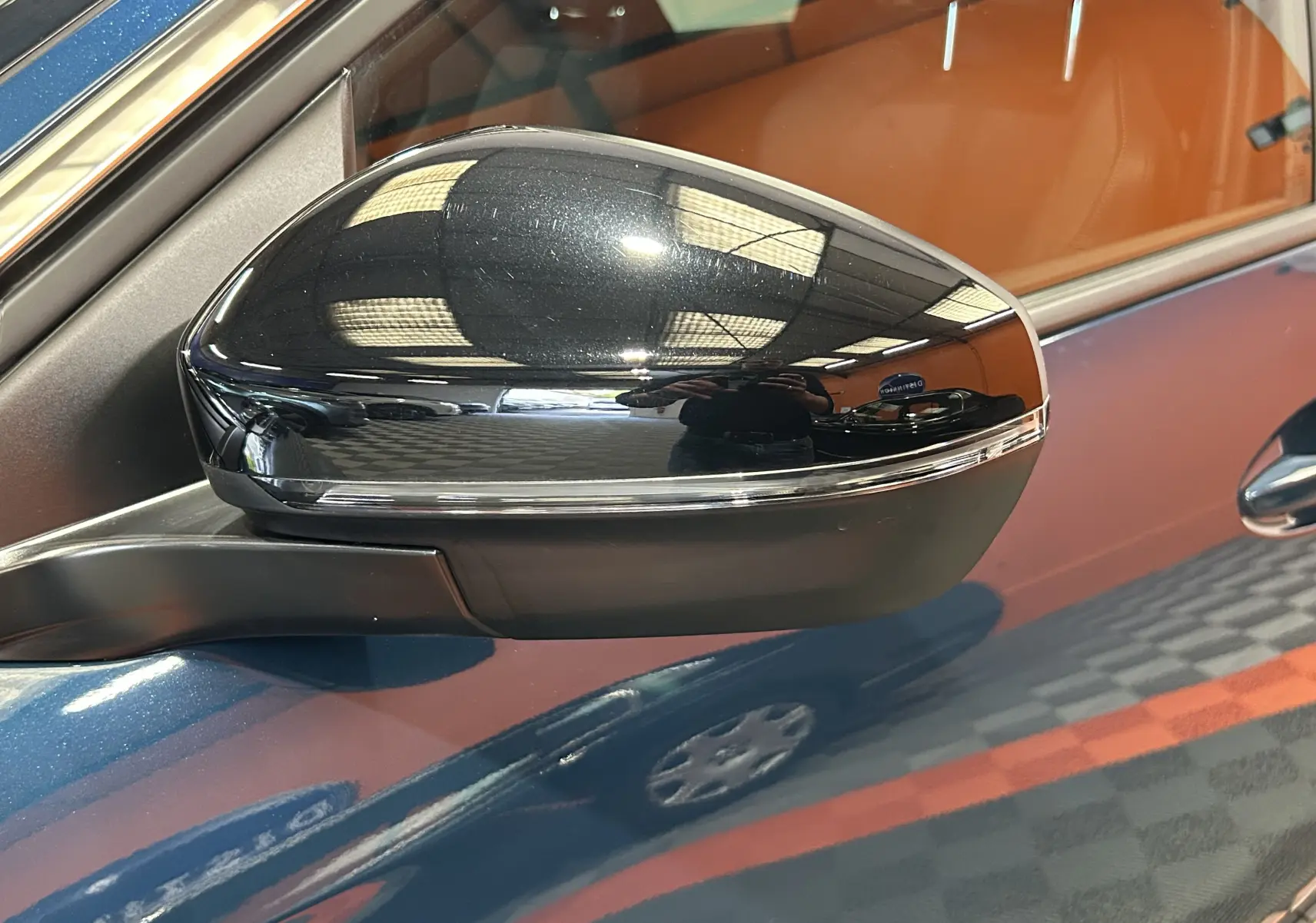 Rétroviseur droit noir brillant du Peugeot 5008 Bleu Célèbes, vue rapprochée avec reflet intérieur brun.