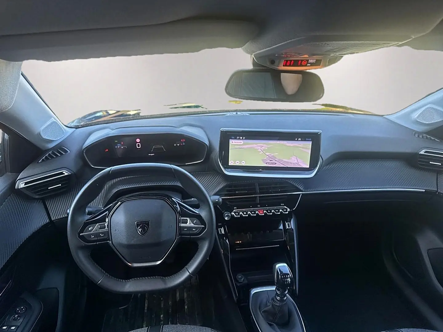 Vue intérieure avant de la Peugeot 208 1.2 100 allure noire, volant compact et écran tactile central avec navigation affichée.