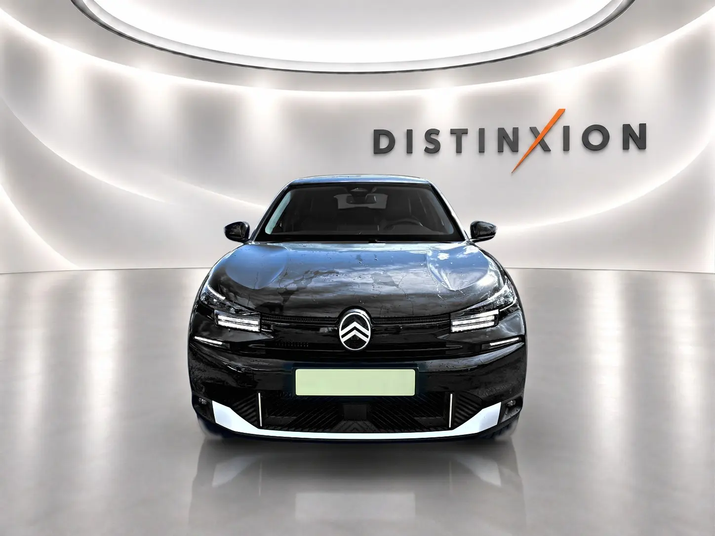 Vue frontale d'une Citroën C4 X noire 2025 avec logo distinctif et éclairage LED dans un showroom lumineux.