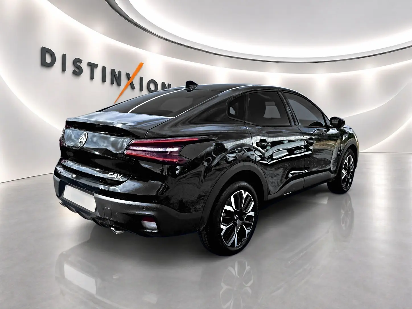 Vue 3/4 arrière droite d'une Citroën C4 X noire brillante avec feux arrière LED et jantes alu distinctives.
