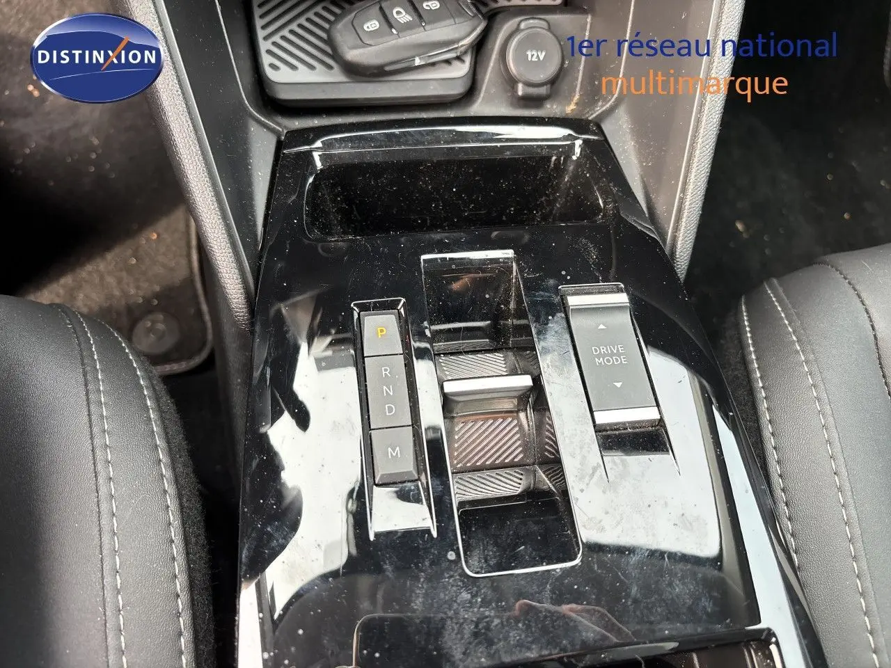 Gros plan sur la console centrale noire brillante de la Citroën C4 Hybrid 145ch, avec sélecteur de boîte auto et bouton Drive Mode.