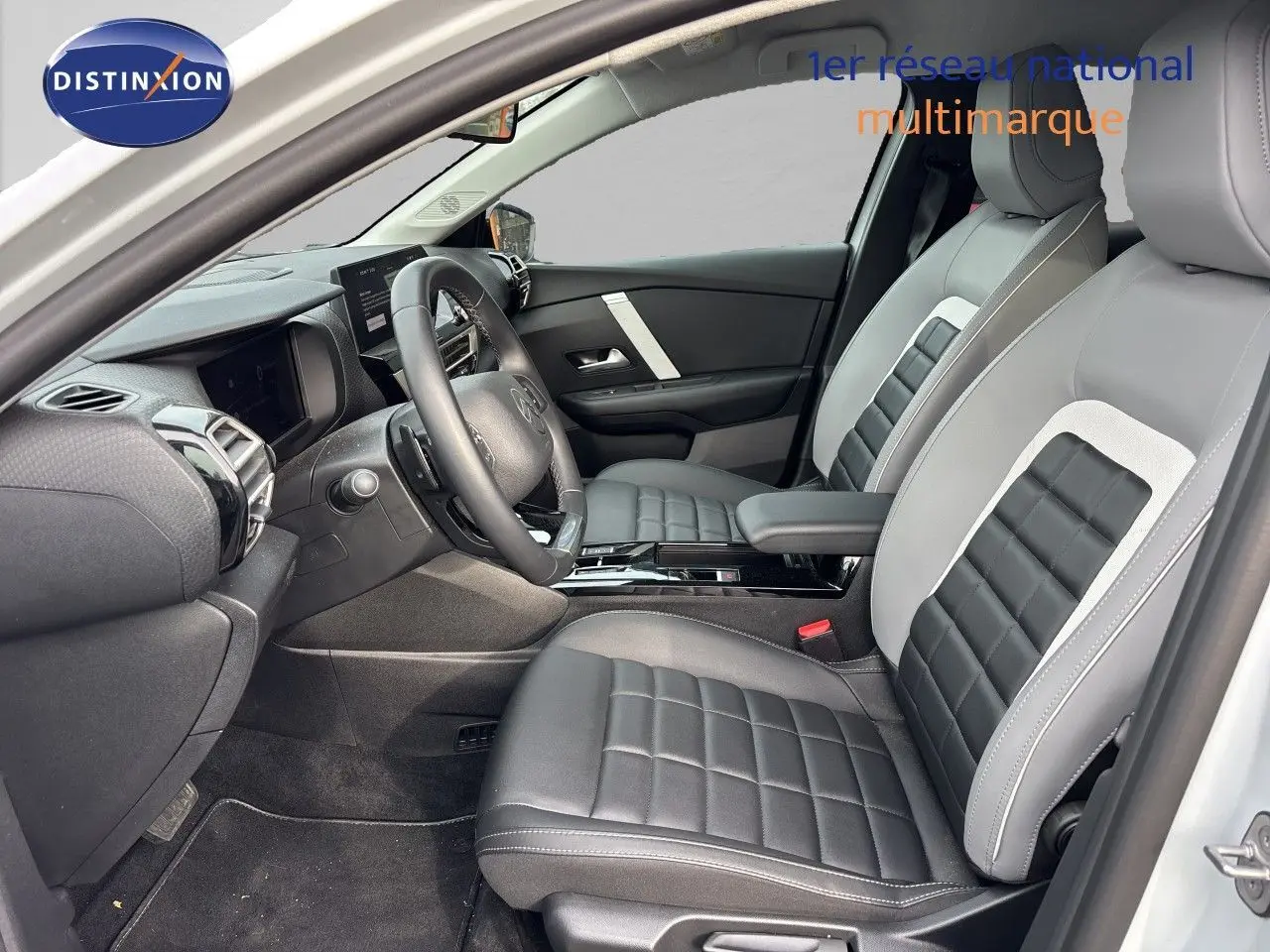 Vue intérieure côté conducteur de la Citroën C4 Hybrid 145ch 2025 avec sièges cuir bicolores gris et noir.