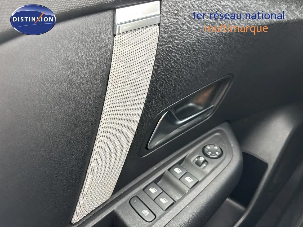 Détail intérieur de la porte côté gauche d'une Citroën C4 blanche, avec commandes des vitres et poignée noire.