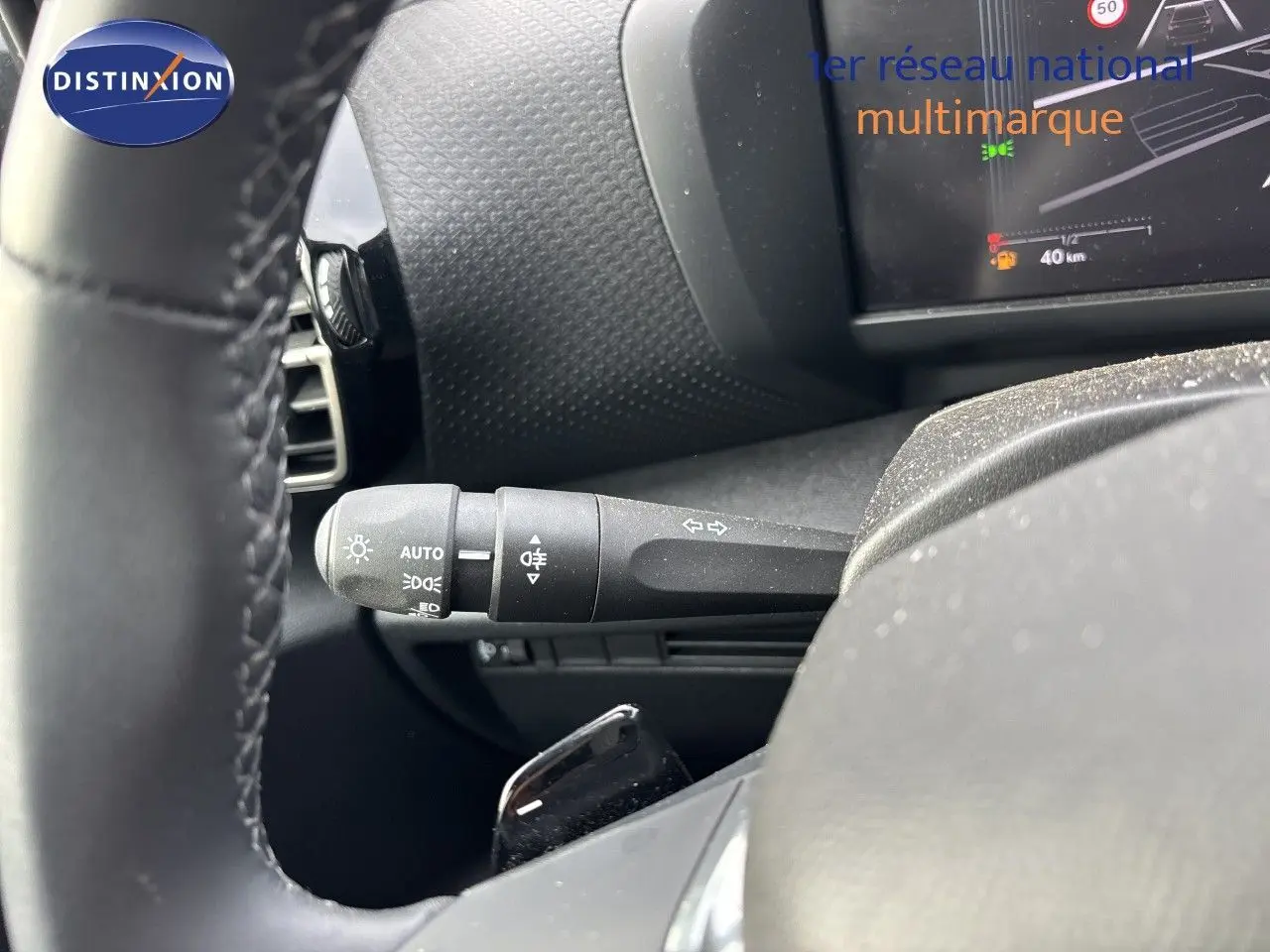 Gros plan sur la manette de clignotant gauche et partie du volant de la Citroën C4 Hybrid blanche, tableau de bord en arrière-plan.