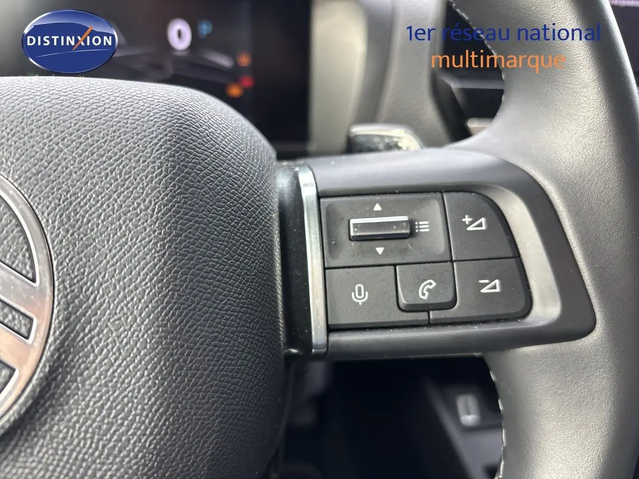 Gros plan sur les commandes au volant noir de la Citroën C4 Hybrid 145ch, intérieur beige visible en arrière-plan.
