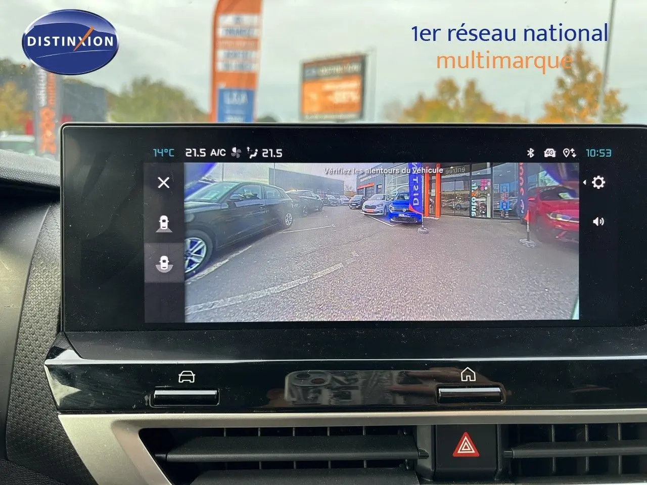 Écran central affichant la caméra de recul d'une Citroën C4 blanche, vue arrière du parking multimarque.