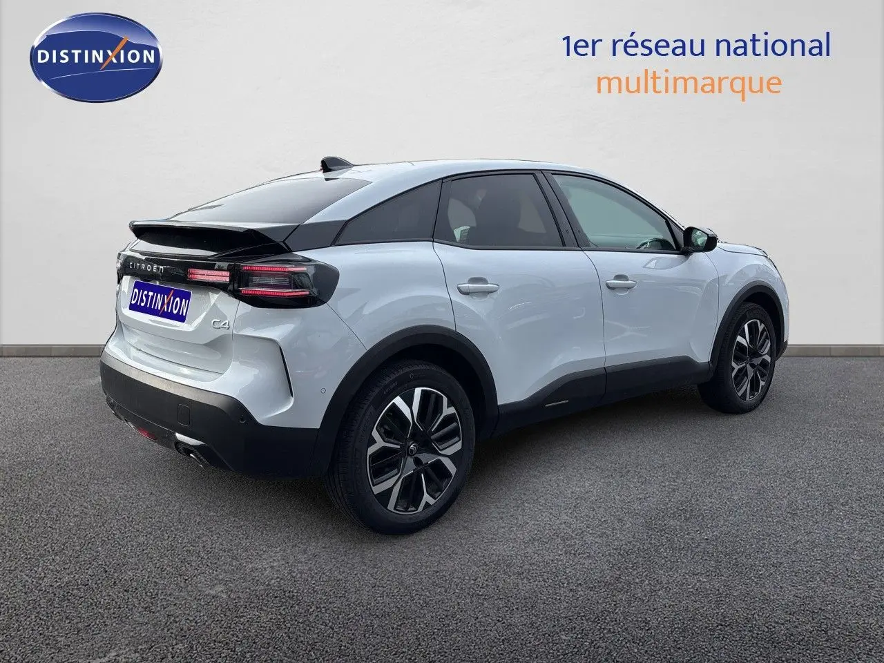 Vue 3/4 arrière droite d'une Citroën C4 Hybrid 145ch blanche Okenite métallisée avec toit noir et jantes bi-ton.