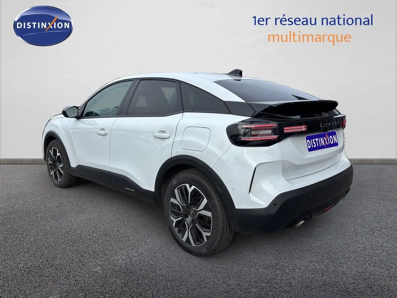 Vue 3/4 arrière droite d'une Citroën C4 hybride blanche Okenite Metal avec jantes bi-ton et toit noir.