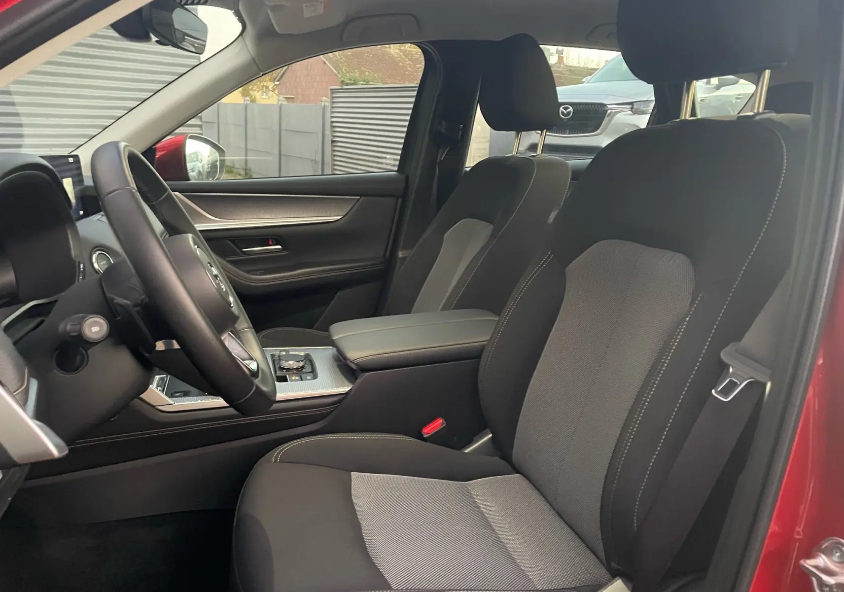 Vue intérieure côté conducteur du Mazda CX-60 Soul Red Crystal 2024, mettant en valeur les sièges tissu et la console centrale moderne.