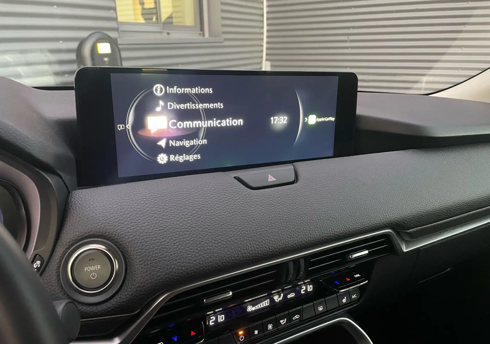 Vue du tableau de bord du Mazda CX-60 2024, écran central affichant le menu communication et commandes climatisation.