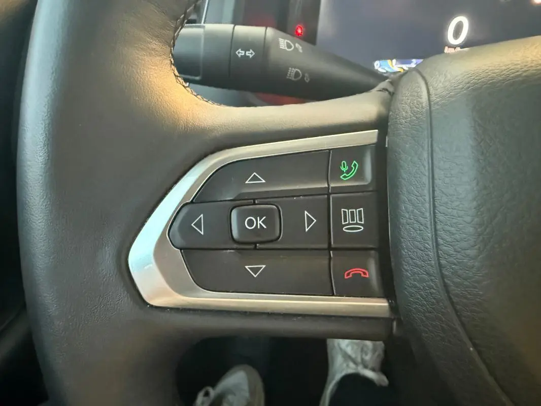 Gros plan sur les commandes du volant en cuir noir du Jeep Renegade 2024, avec boutons de téléphone et navigation.