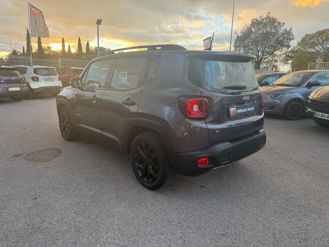 Jeep Renegade gris anthracite en 3/4 arrière droit, avec barres de toit et jantes alliage noires de 18 pouces.