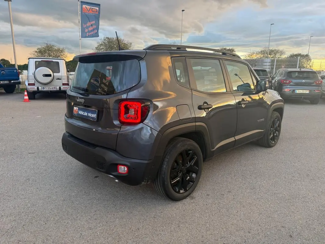 Jeep Renegade gris anthracite vu en 3/4 arrière droit, avec barres de toit et jantes alliage noires de 18 pouces.
