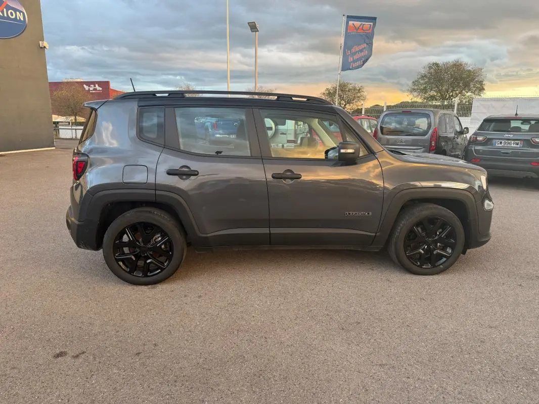 Profil côté gauche d'un Jeep Renegade gris anthracite 2024 avec jantes alliage noires et barres de toit visibles.