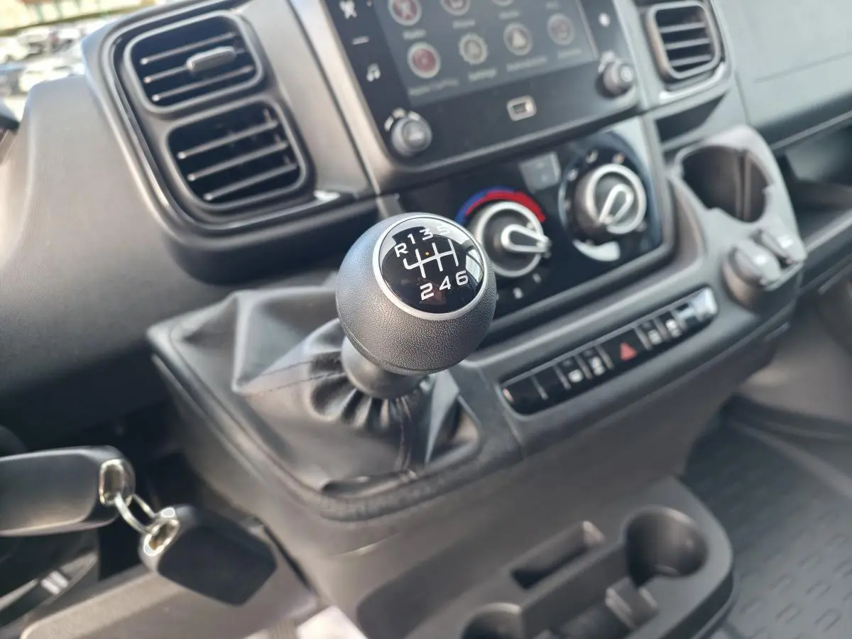 Gros plan sur le levier de vitesses manuel du Fiat Ducato Fourgon blanc, avec tableau de bord et commandes visibles.