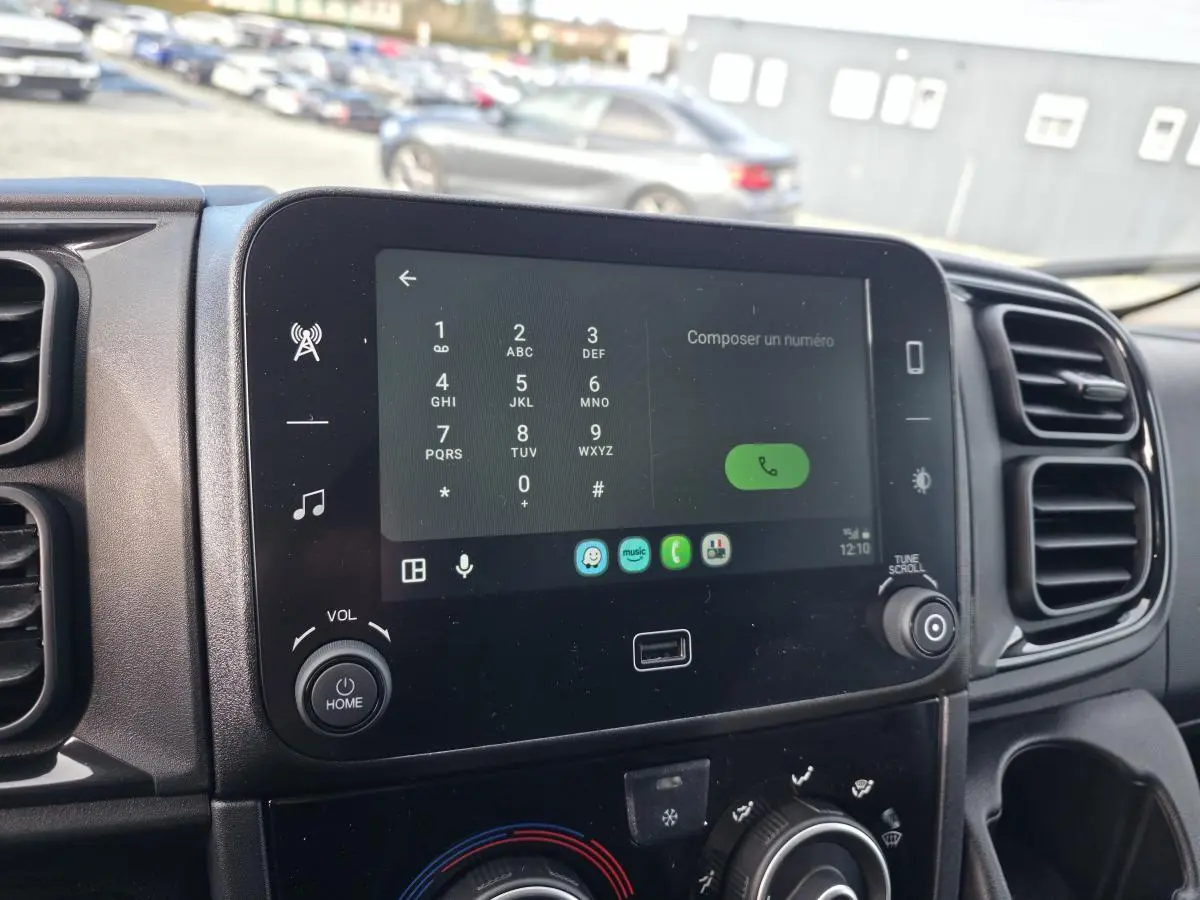 Écran tactile 7 pouces du tableau de bord du Fiat Ducato Fourgon blanc, avec commandes multimédia et climatisation.
