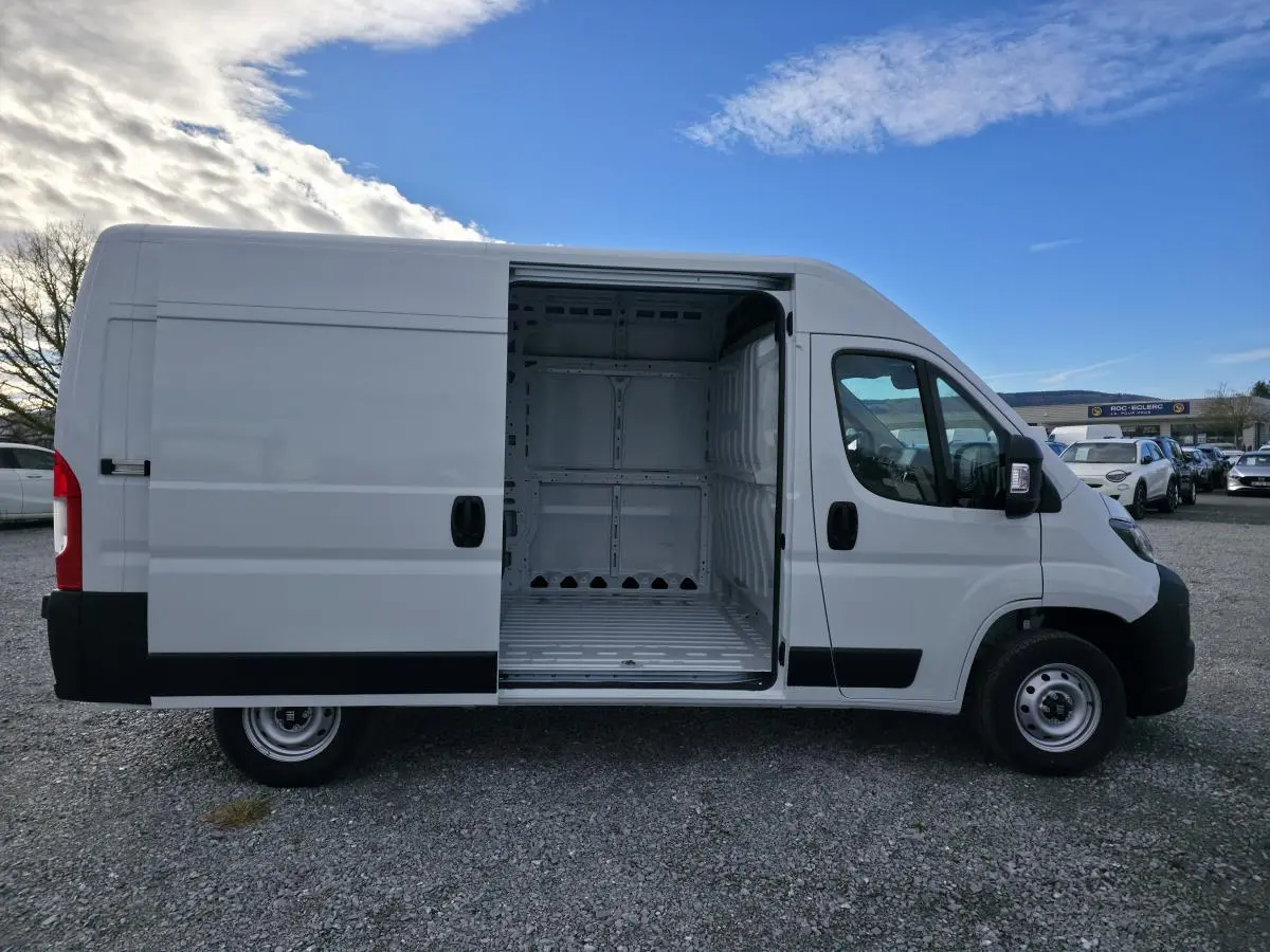 FIAT Ducato Fourgon blanc vue de profil droit avec porte latérale coulissante ouverte montrant l’intérieur tôlé vide.