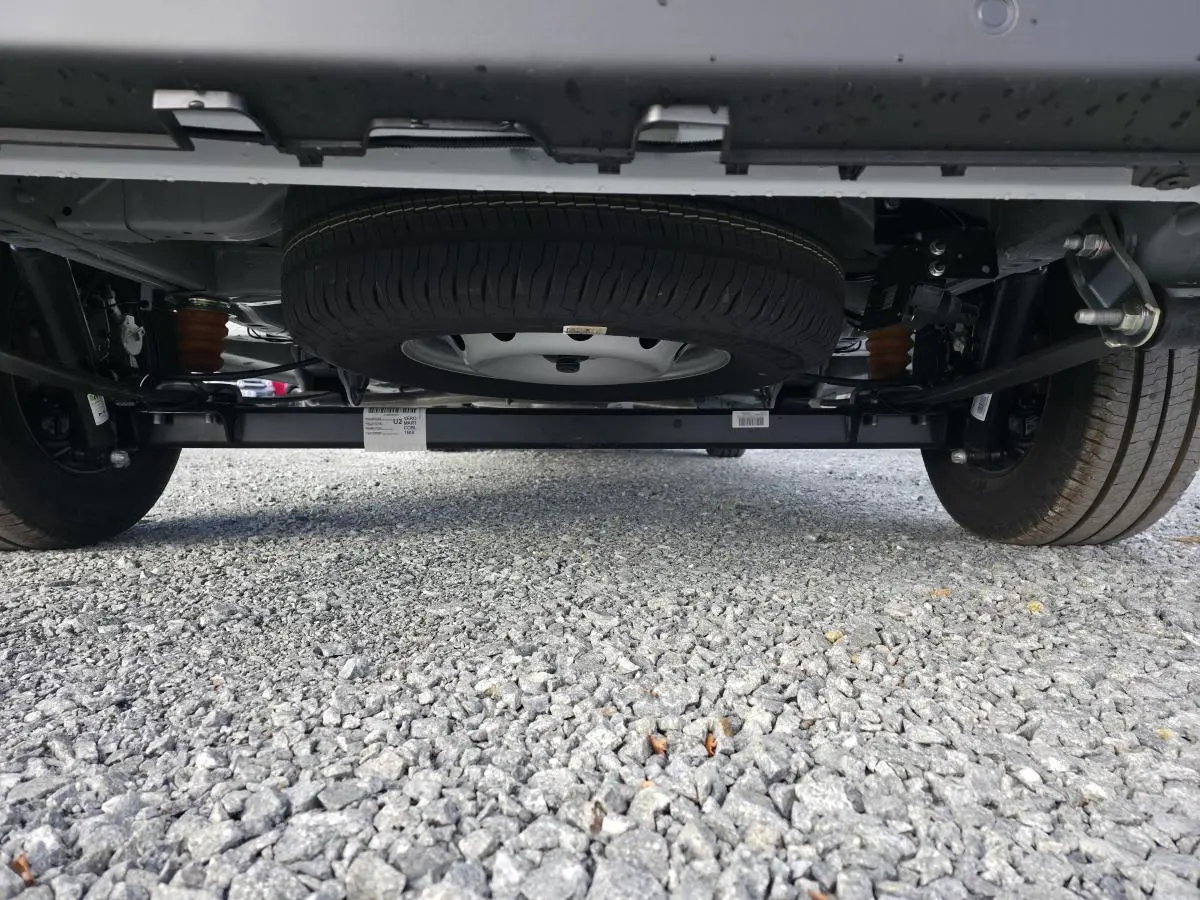 Vue en contre-plongée sous un Fiat Ducato Fourgon blanc, montrant la roue de secours et le châssis arrière.