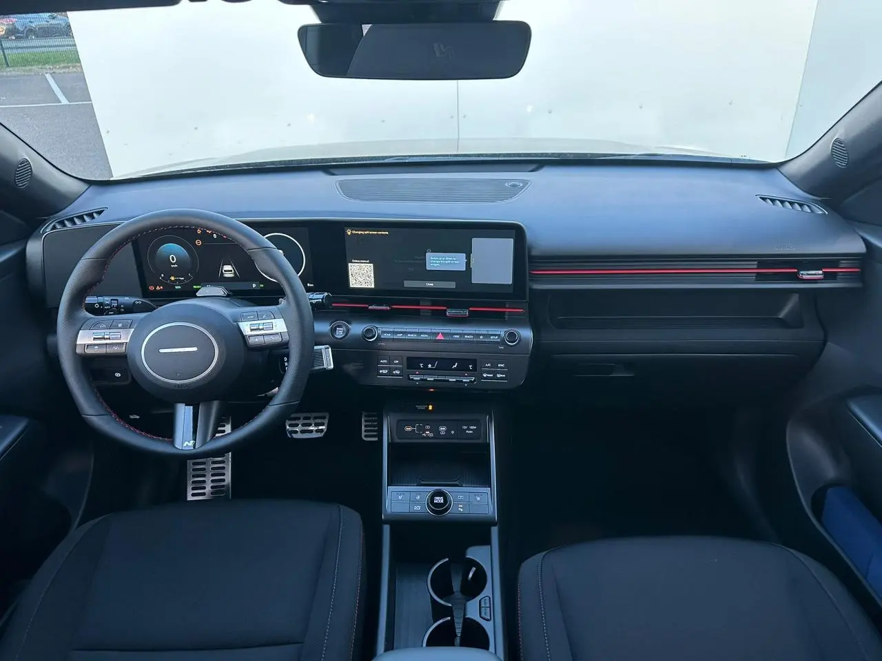 Vue intérieure avant du Hyundai Kona 2026 gris Ecotronic, tableau de bord numérique avec écran tactile large et volant cuir.