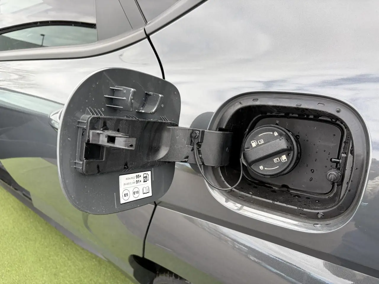 Vue rapprochée de la trappe à carburant ouverte côté gauche d’un Hyundai Kona 2026 gris métallisé.