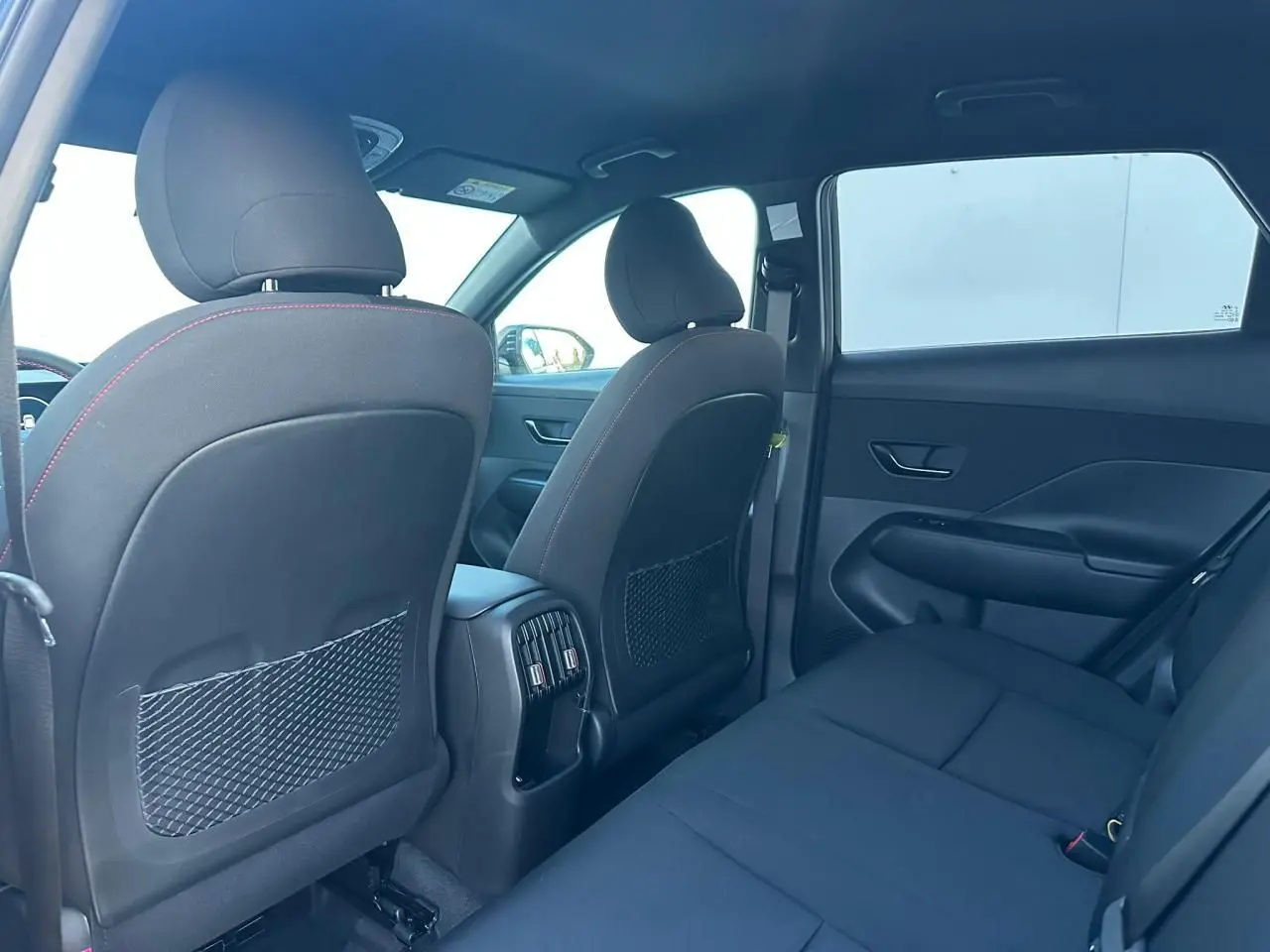 Vue intérieure arrière du Hyundai Kona II gris, montrant les sièges arrière et les dossiers des sièges avant avec prises USB-C.