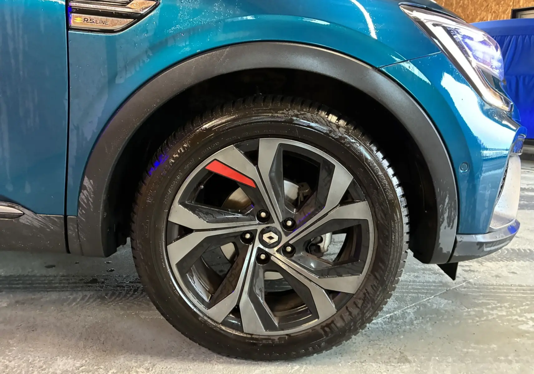 Vue intérieure de la porte avant gauche ouverte d’un Renault Arkana bleu, avec commandes électriques et éclairage d’ambiance bleu.