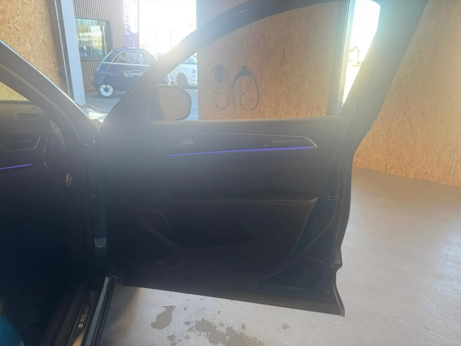 Portière avant gauche ouverte d'une Renault Arkana bleu 1.3 TCE 140 RS-LINE, avec éclairage d'ambiance violet visible.