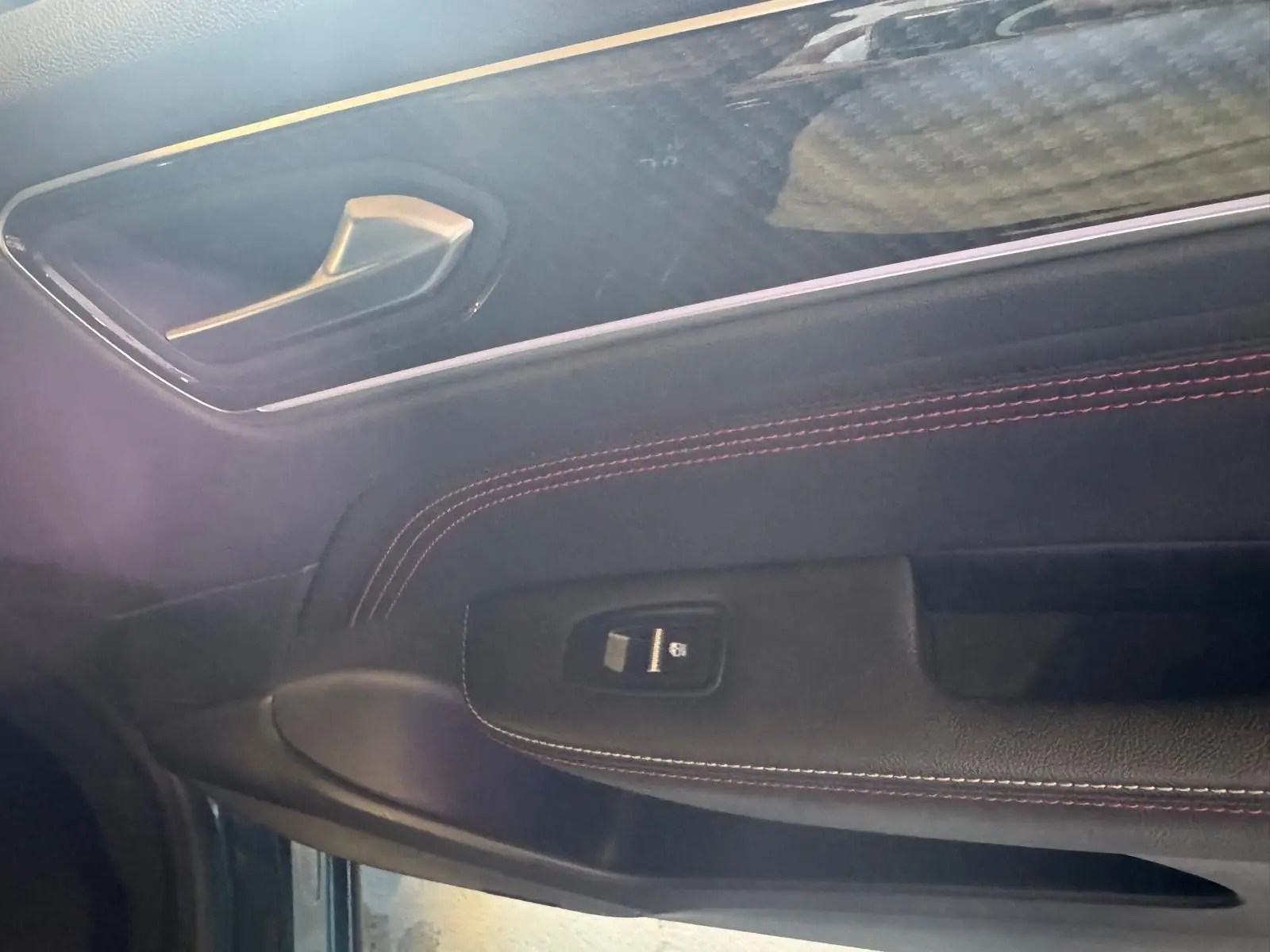 Détail de la porte côté gauche du Renault Arkana bleu 2021, avec surpiqûres rouges et commande de vitre électrique.