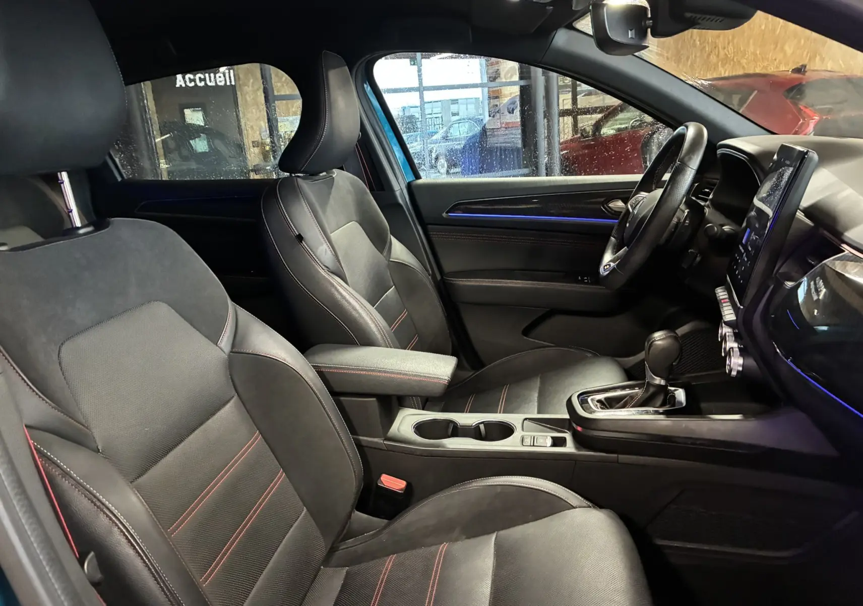 Vue intérieure côté conducteur de la Renault Arkana 1.3 TCE 140 RS-Line 2021, sièges cuir noir avec surpiqûres rouges et console centrale.