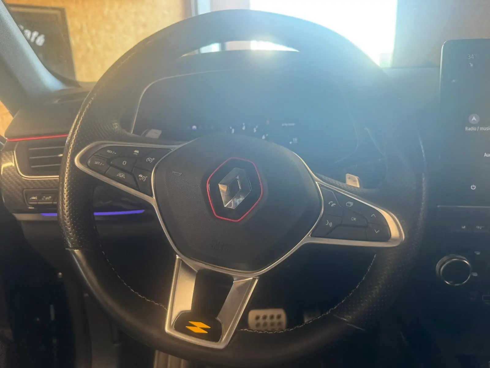 Gros plan sur le volant noir perforé du Renault Arkana 1.3 TCE 140 RS-LINE avec logo rouge et commandes intégrées.