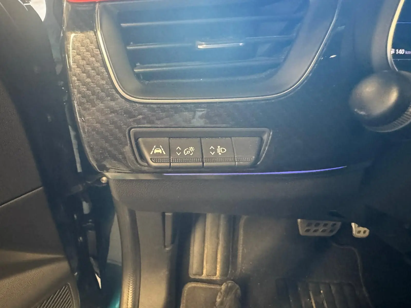 Détail intérieur côté gauche du tableau de bord du Renault Arkana bleu 1.3 TCE 140 RS-LINE avec commandes d’assistance et pédales visibles.