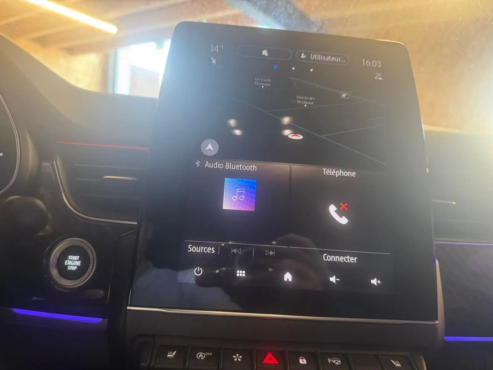 Écran tactile central allumé avec navigation et commandes multimédia dans l'habitacle noir du Renault Arkana bleu.