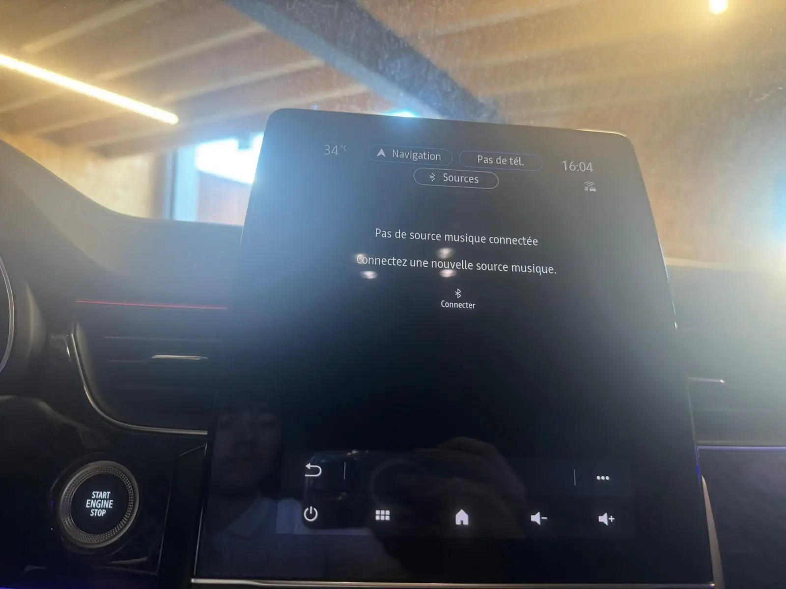 Écran tactile central du tableau de bord du Renault Arkana bleu, vue rapprochée en intérieur avec bouton start visible.