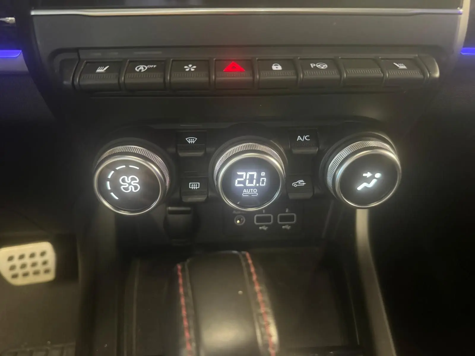 Gros plan sur la console centrale du Renault Arkana bleu 2021, montrant les commandes de climatisation et les boutons de fonction.