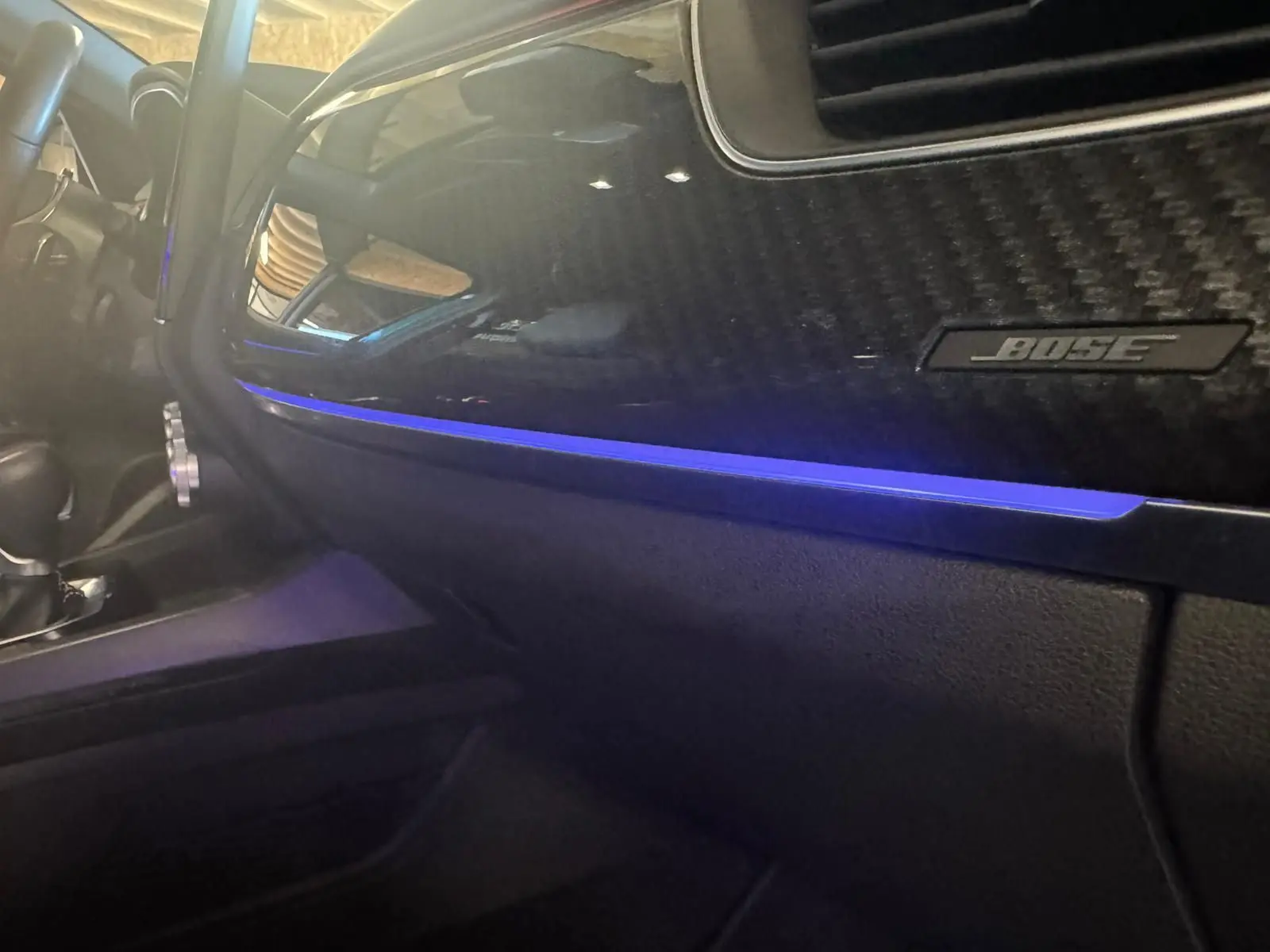 Vue intérieure côté passager du tableau de bord noir avec éclairage d'ambiance bleu et logo Bose sur Renault Arkana 1.3 TCE 140 RS-Line.