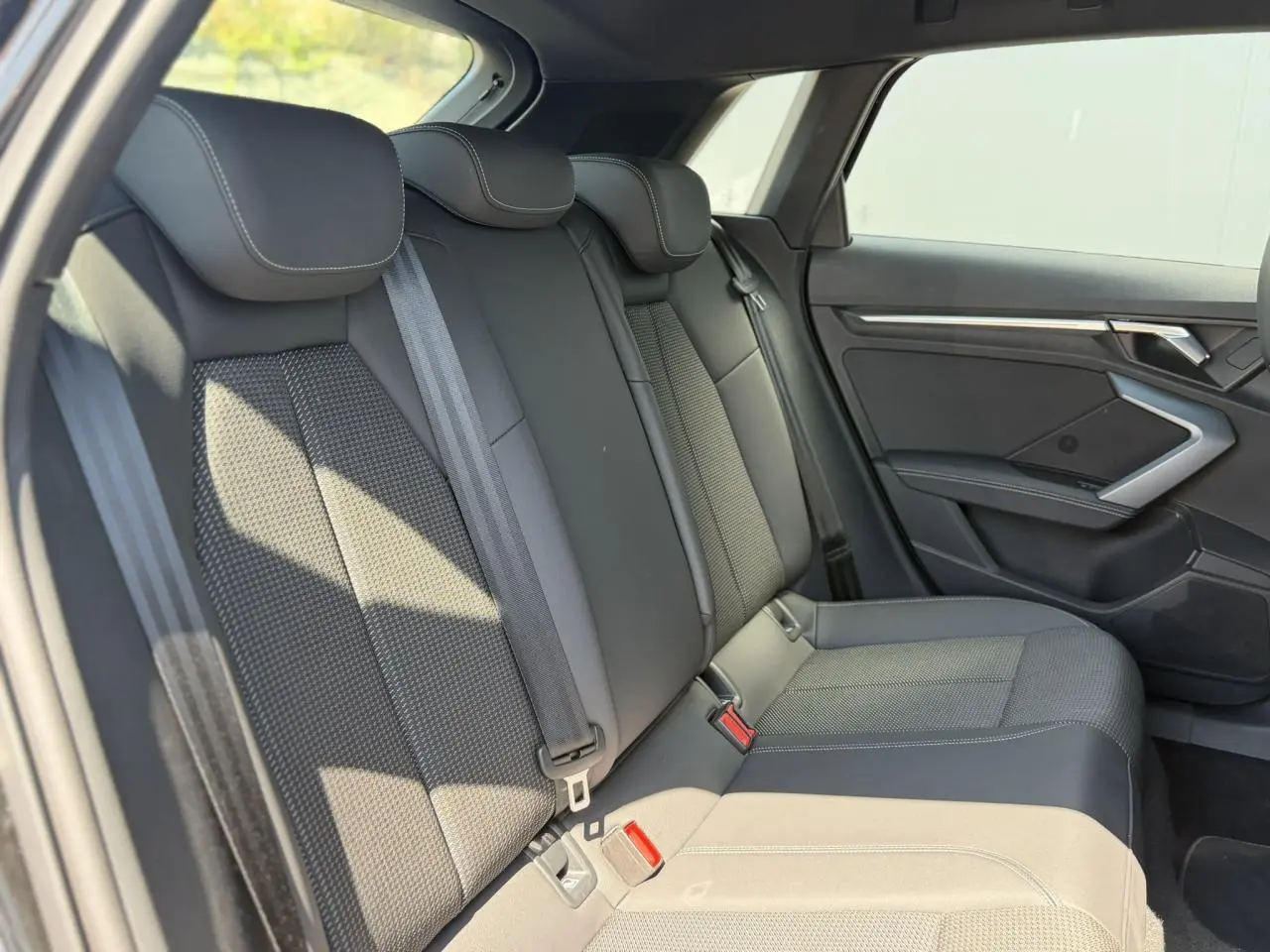 Vue latérale droite de la banquette arrière noire de l'Audi A3 Sportback 2025 avec ceinture et garnitures en tissu et cuir.