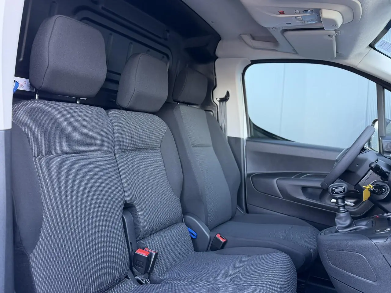 Vue intérieure côté droit du Peugeot Partner 2026 blanc Icy, montrant la banquette passager 2 places en tissu gris.