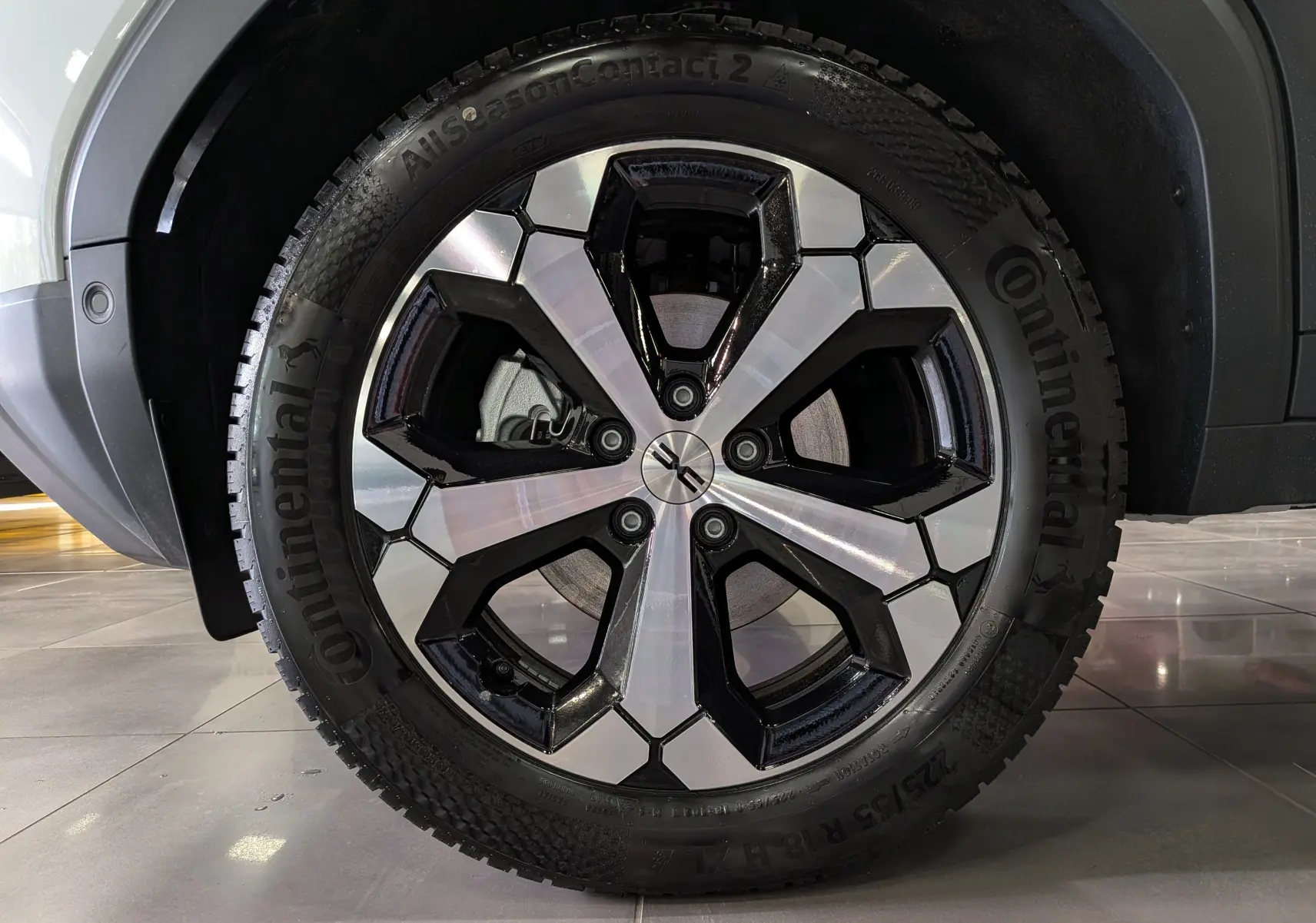Gros plan sur la roue avant droite du Dacia Duster blanc Glacier, avec jante alliage bicolore et pneu Continental.