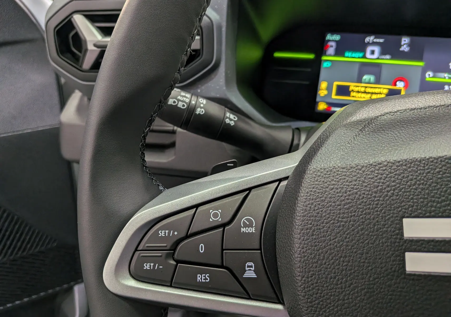 Gros plan sur le volant côté gauche du Dacia Duster blanc Glacier 2026, avec commandes de régulateur et tableau de bord numérique.