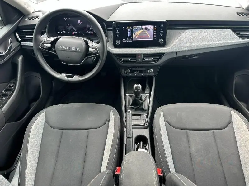 Vue intérieure avant du Skoda Scala blanc cristal 2025, volant cuir multifonction, écran tactile et levier de vitesse manuel.